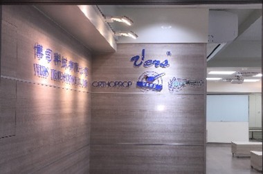 2020年 VERS 科技教育中心入口形象牆，木紋牆面結合多項核心技術品牌標誌，右側為明亮的室內健康推廣與教育訓練空間